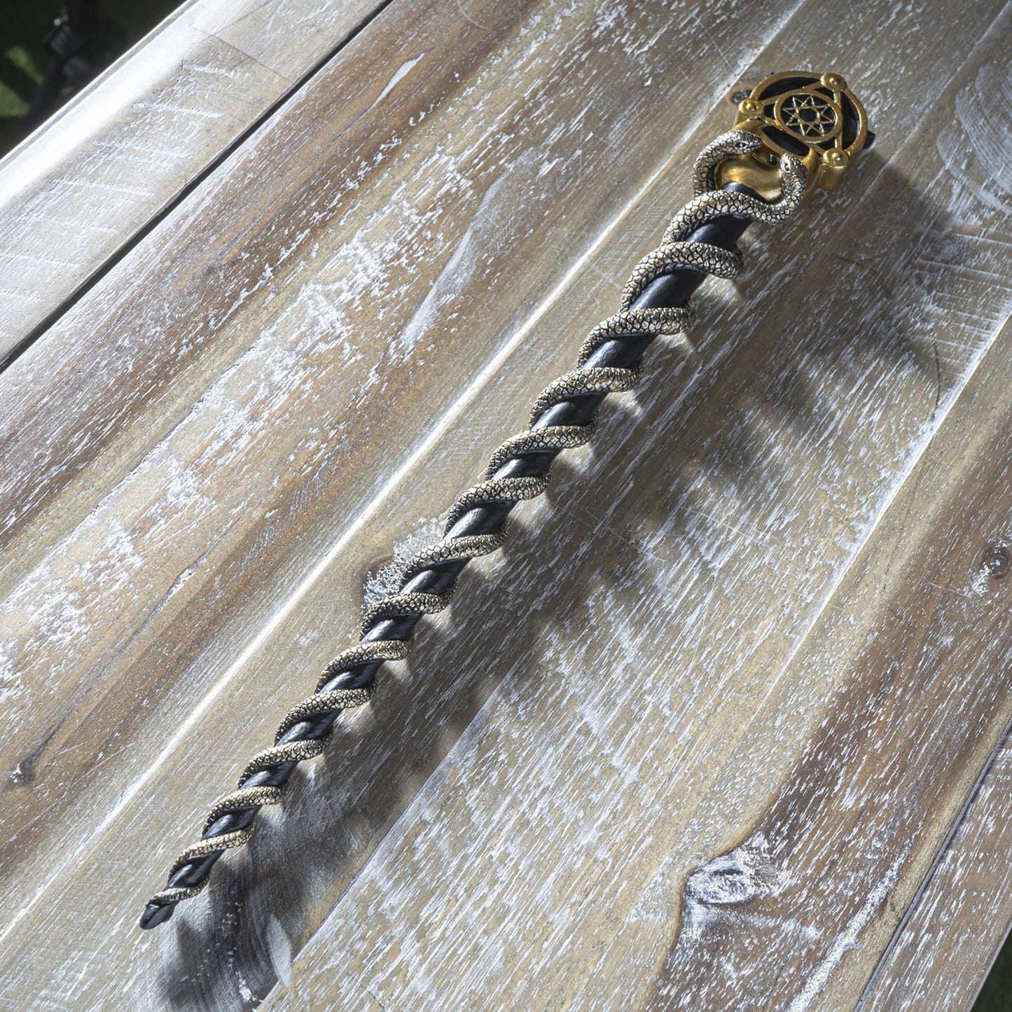 Magic Wand with braided design and decorative clasp on a wooden surface