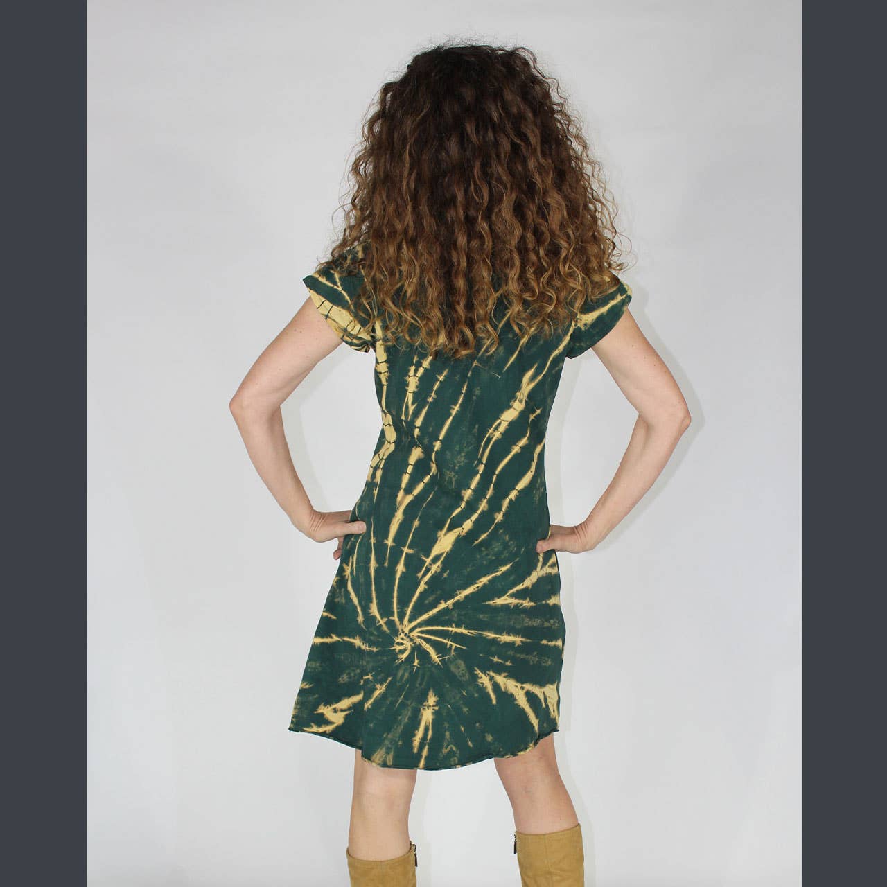 Person wearing a green and gold tie-dye dress against a plain background