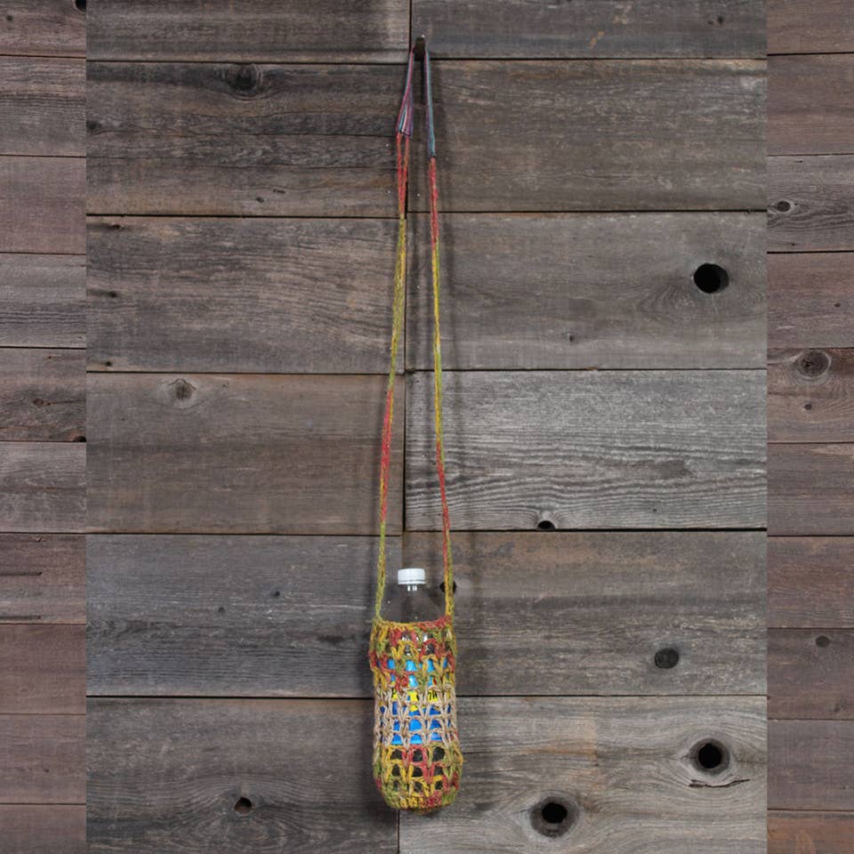 Colorful woven bag with a bottle hanging on a wooden wall