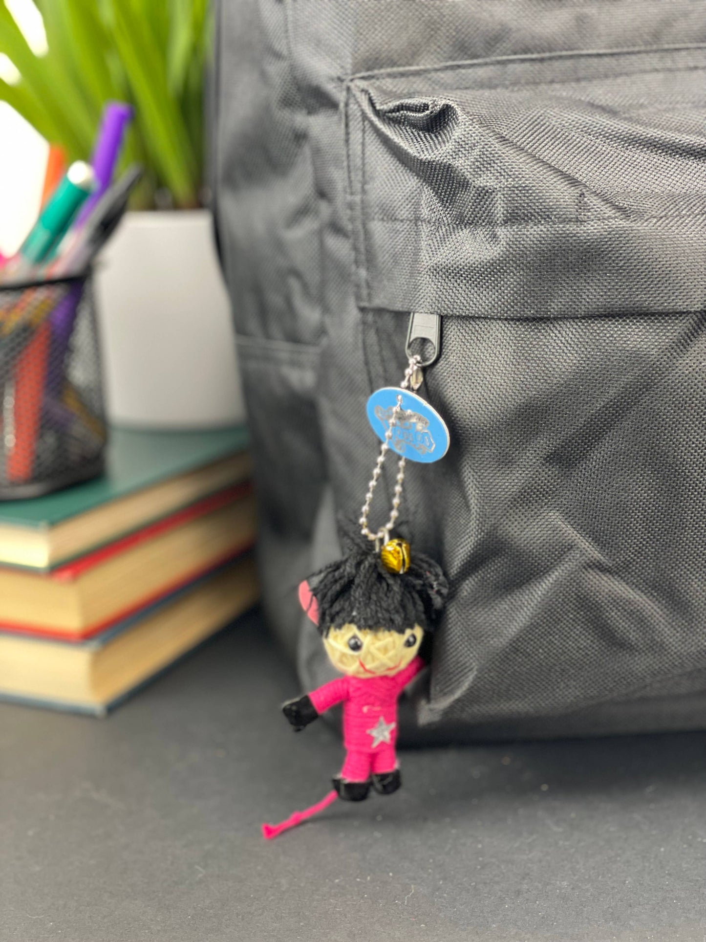 Keychain attached to a gray bag with books and stationery items in the background