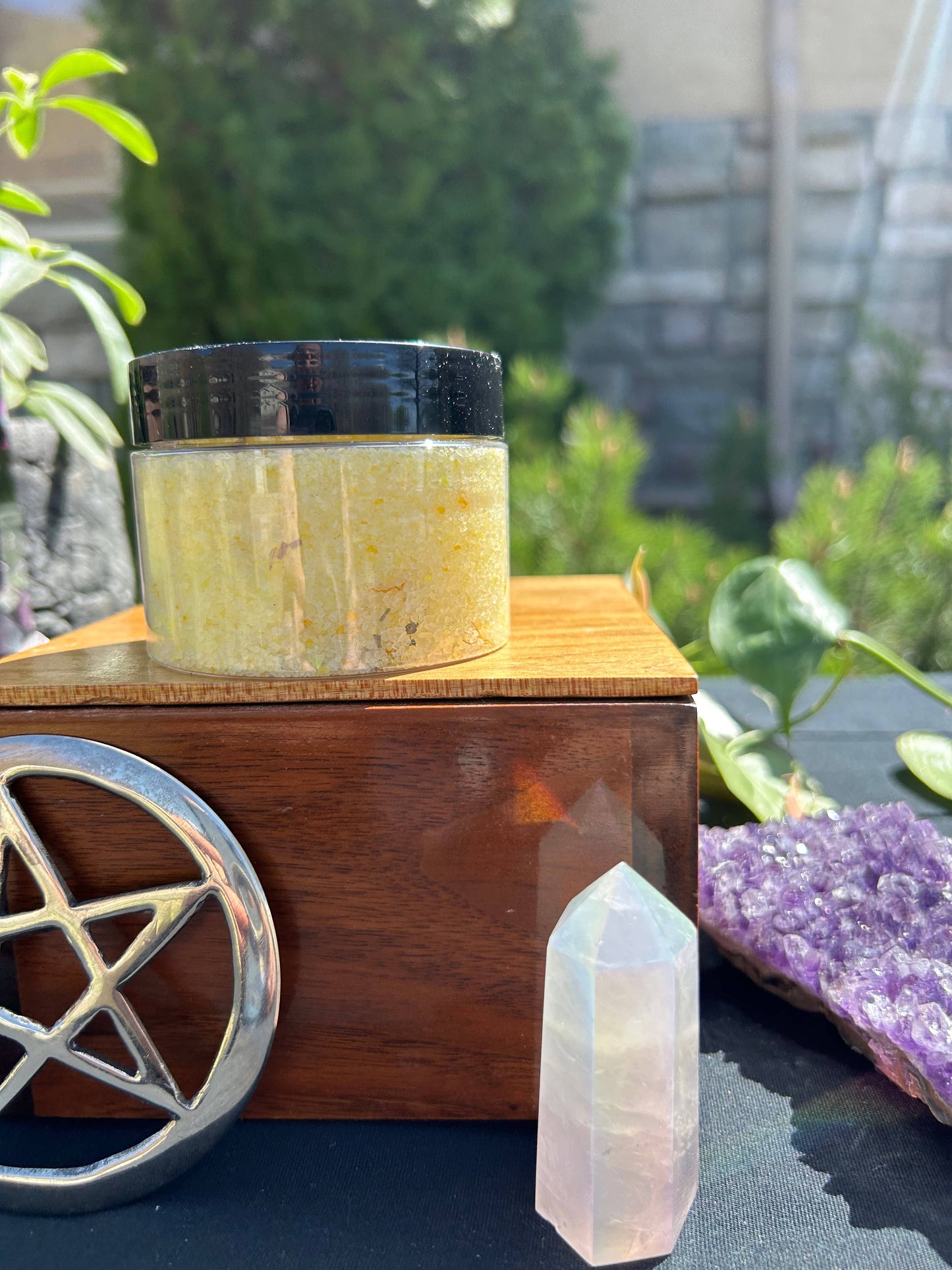 Jar of yellow powder on a wooden block with crystals and plants in the background