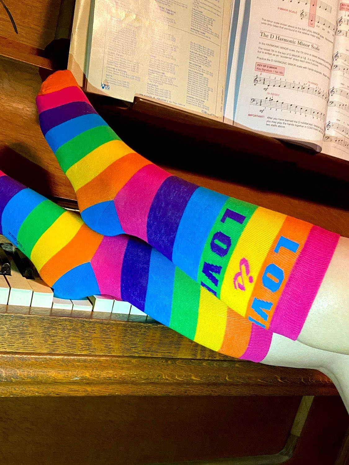 Colorful striped socks with 'LOVE' text on a piano with sheet music.
