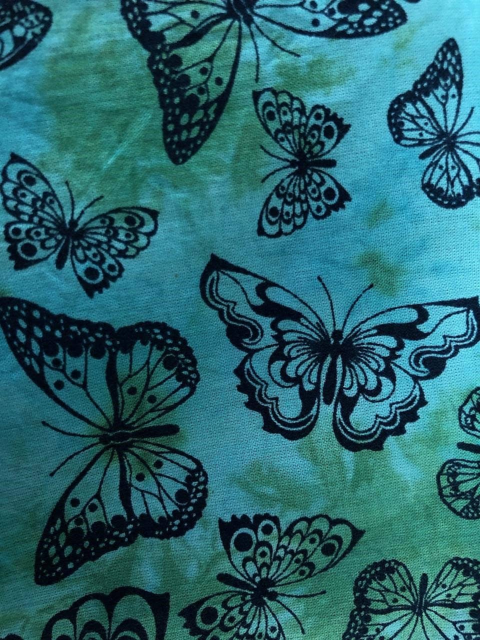 Pattern of black butterflies on a teal fabric background
