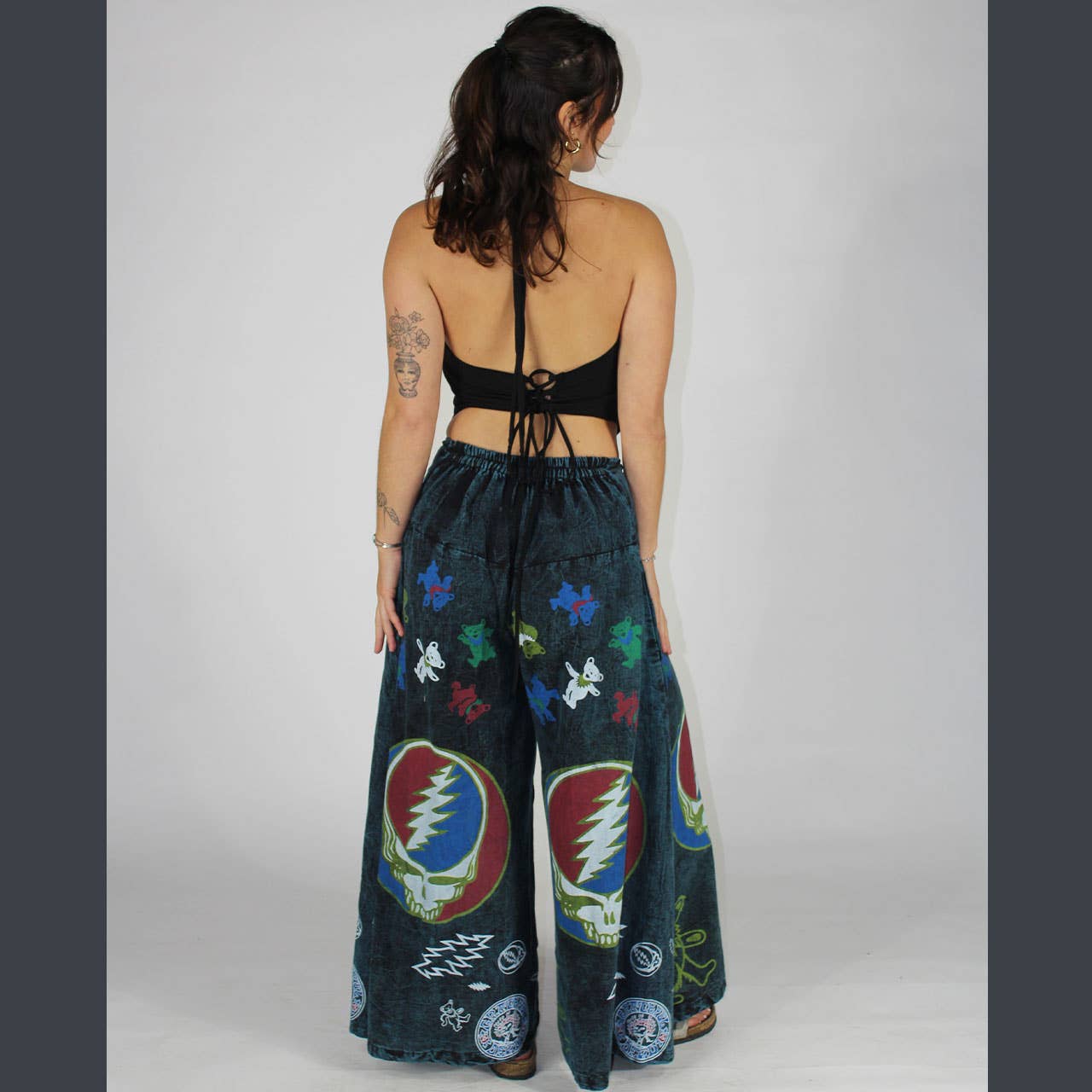 Woman wearing dark blue pants with colorful symbols on a plain background