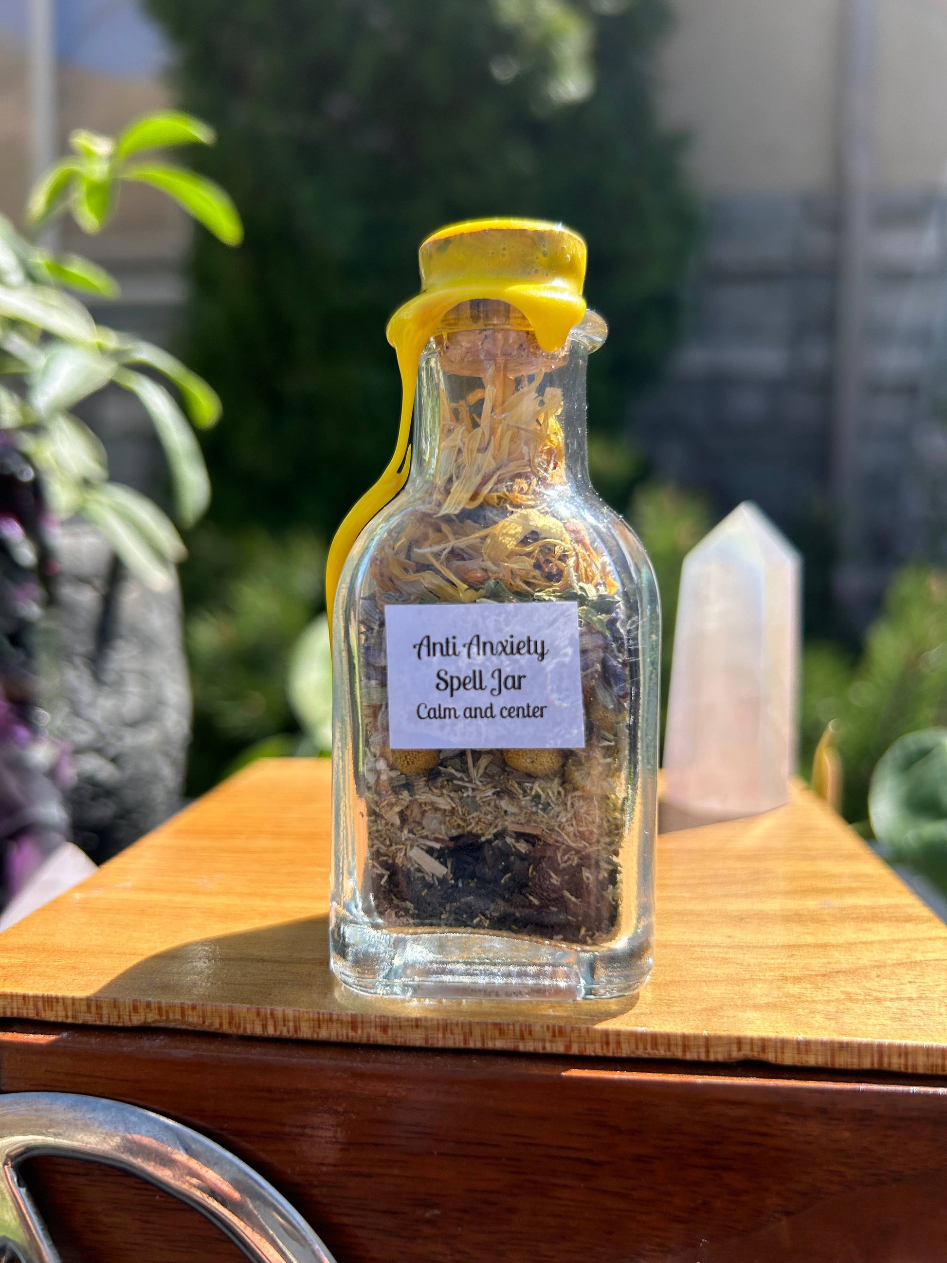 Glass jar labeled 'Anti-Anxiety Spell Jar' with yellow lid on a wooden surface.