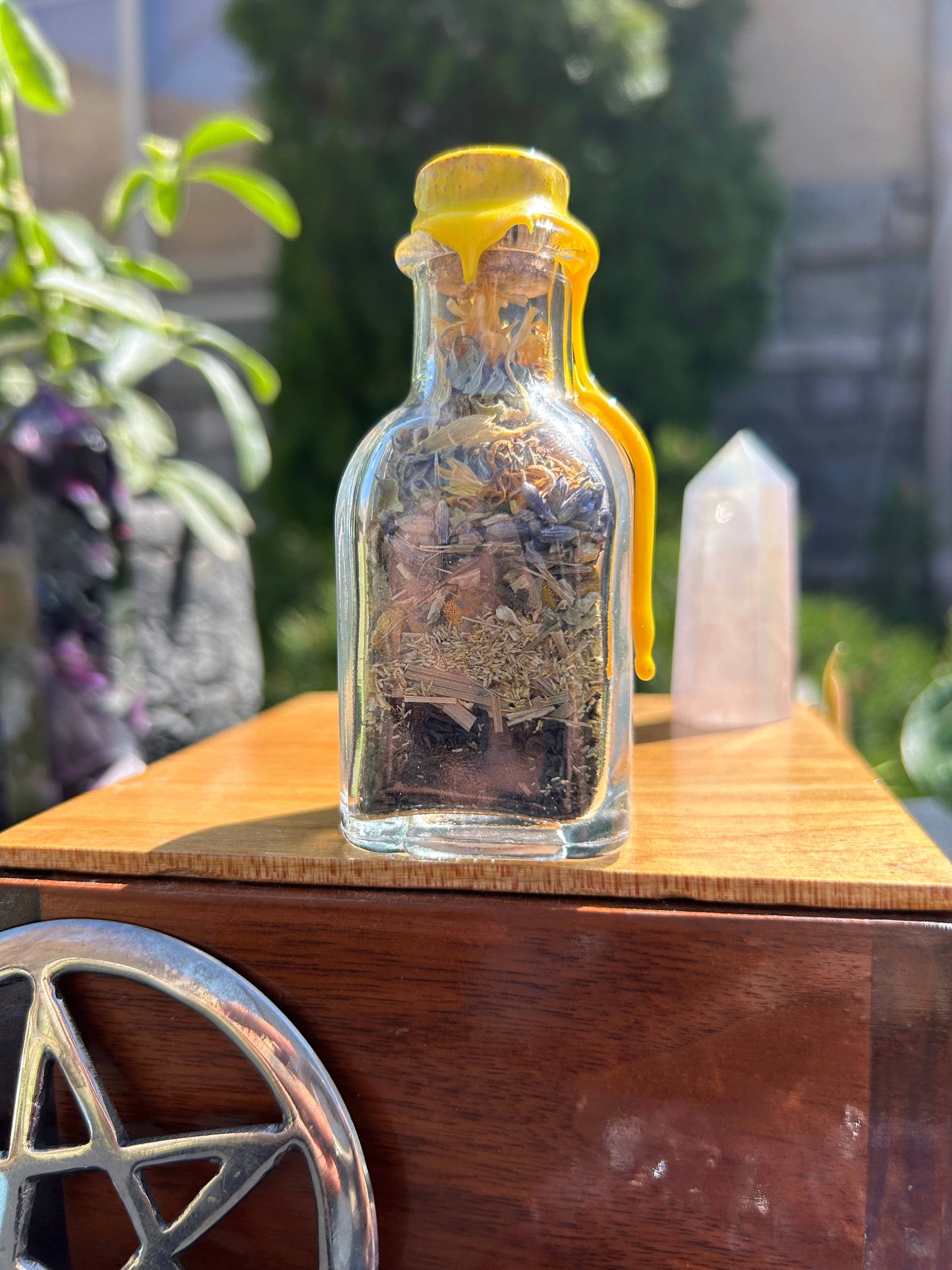 Small glass bottle with a yellow cap on a wooden surface outdoors
