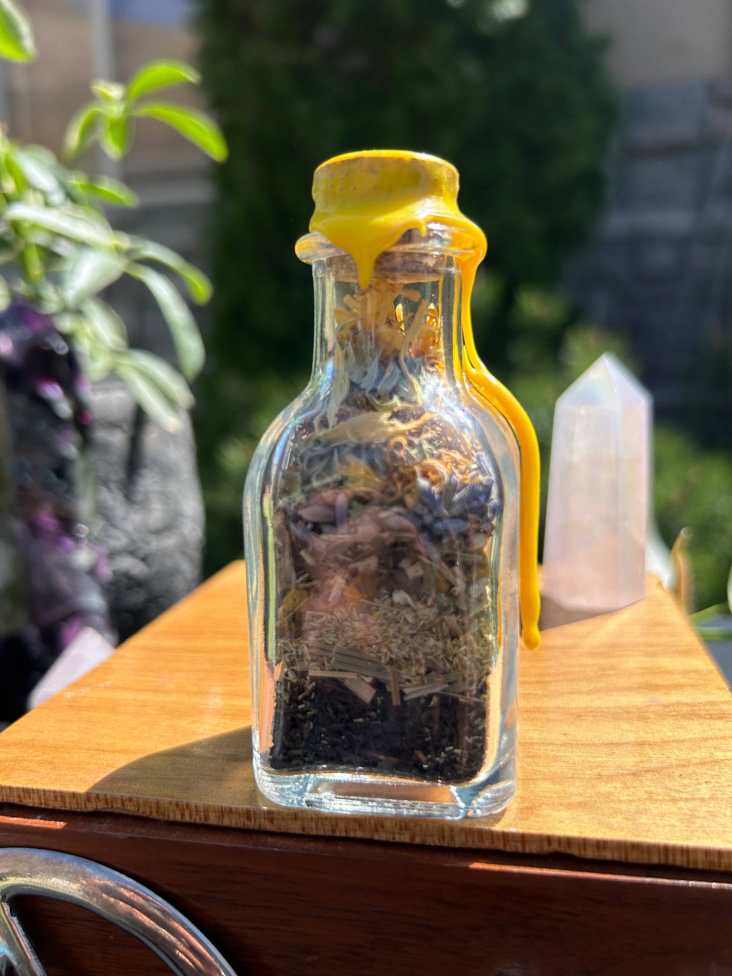 Clear glass bottle with yellow cap on a wooden surface outdoors