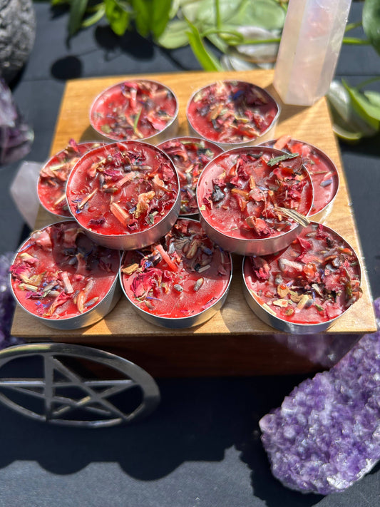 Red wax melts in metal containers on a wooden board with crystals and a pentacle symbol in the background.