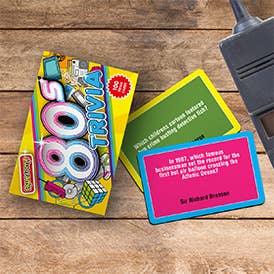 Colorful trivia cards on a wooden surface with a remote control.
