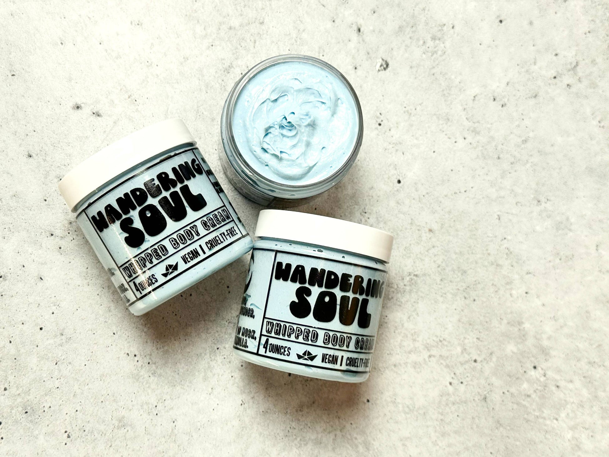 Two jars of 'Wandering Soul' whipped body butter on a textured surface