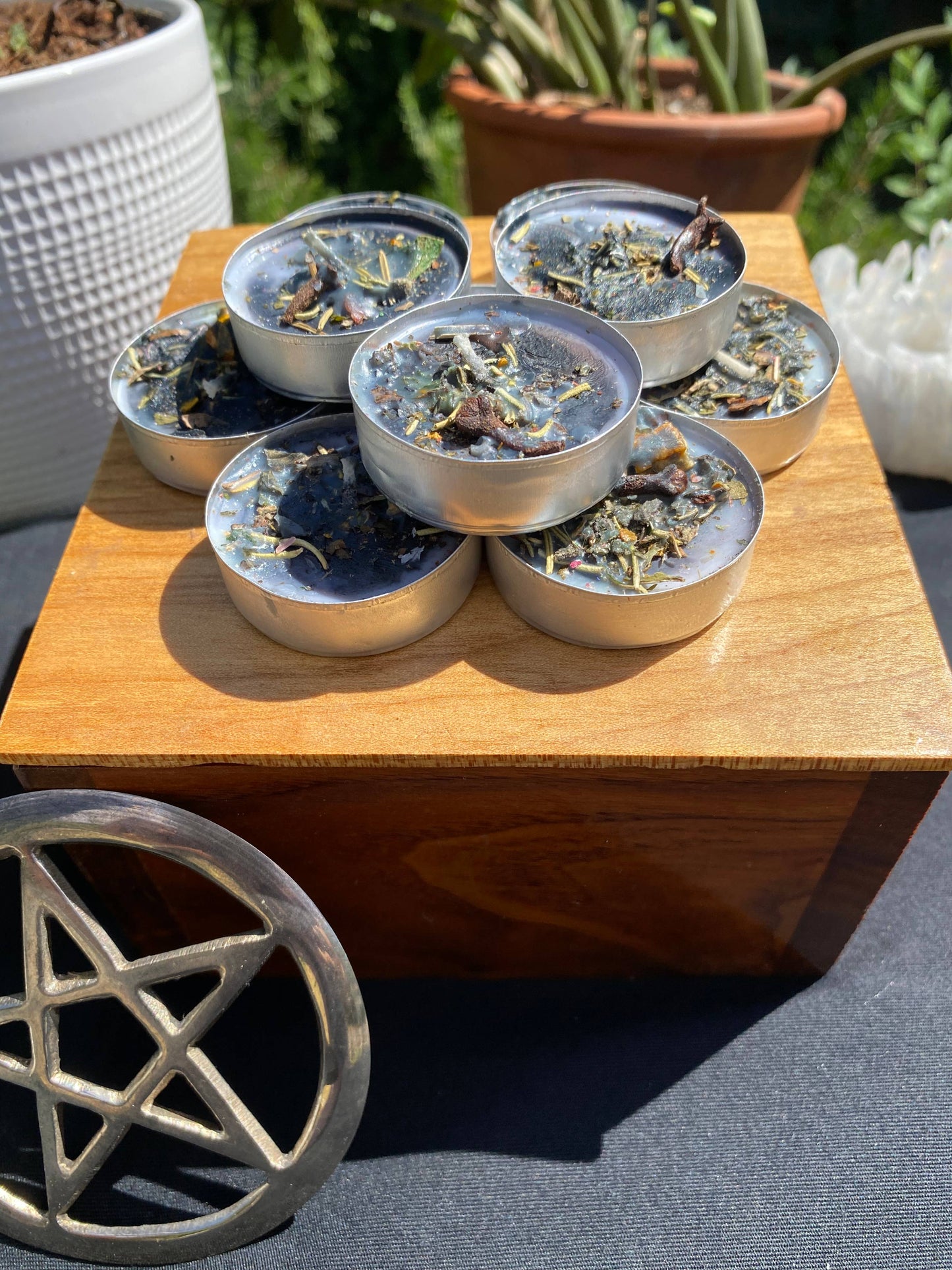 Small metal bowls with dried herbs on a wooden table outdoors