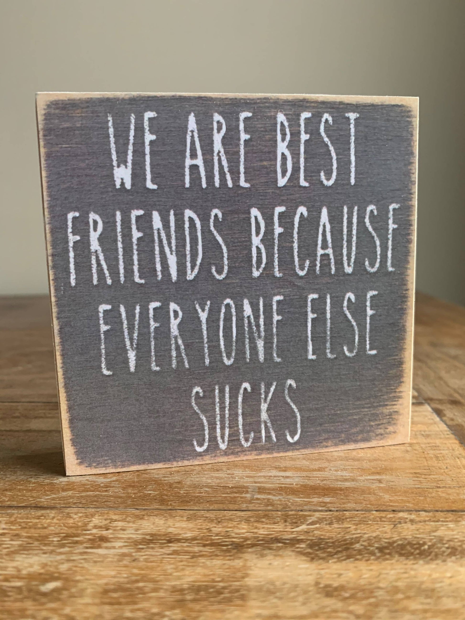 Wooden sign with humorous text on a wooden surface