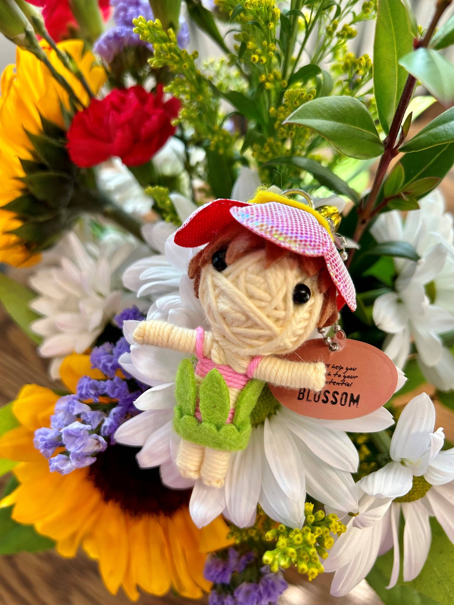 Small figurine of a girl in a red hat among flowers with a 'Blossom' tag.