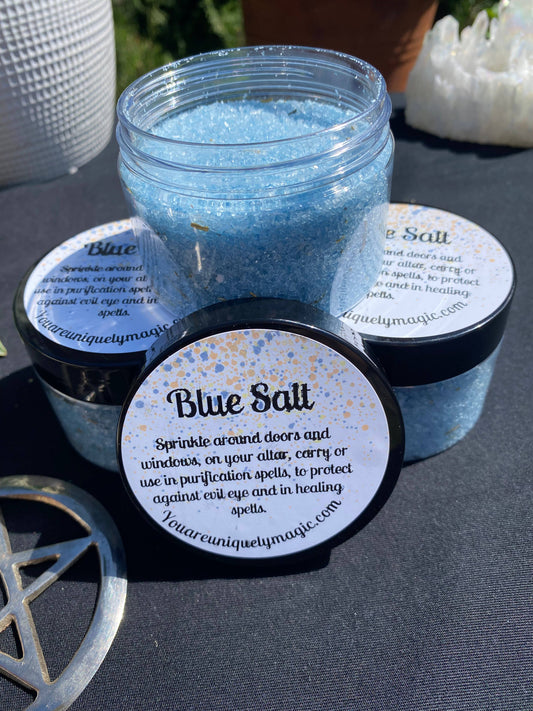 Jar of blue salt with a label on a dark surface