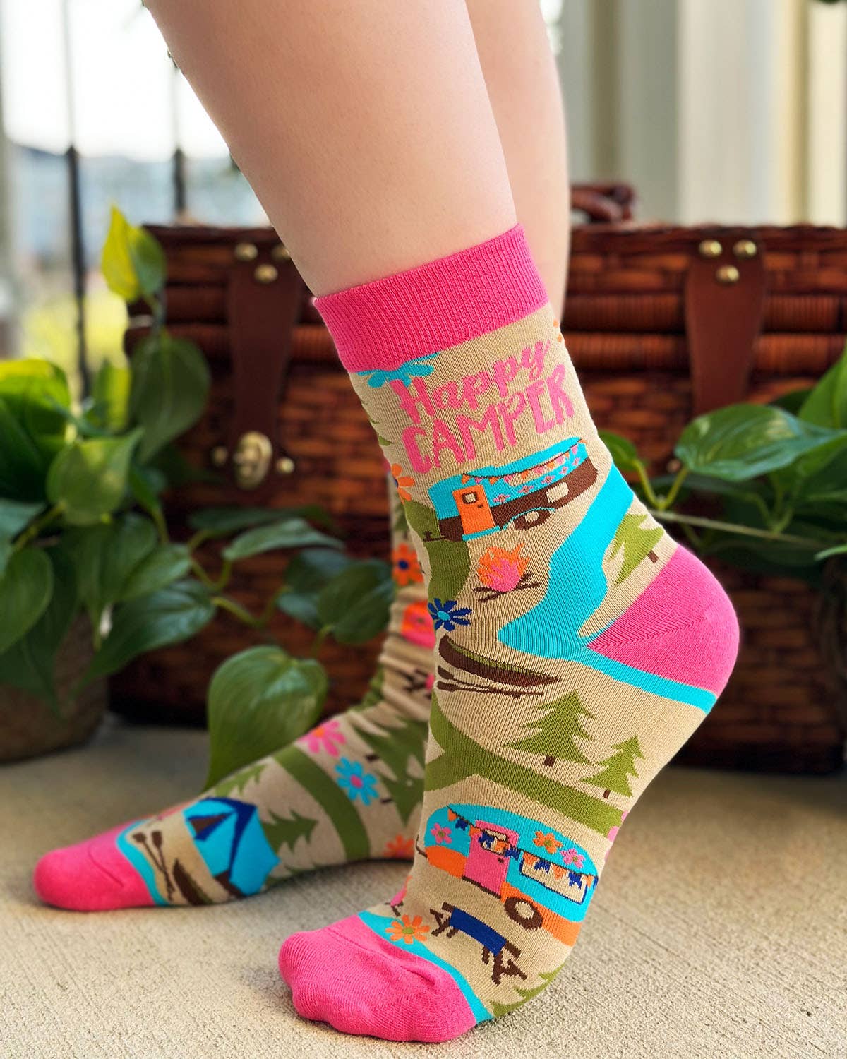 Colorful 'Happy Camper' socks worn by a person with a blurred background