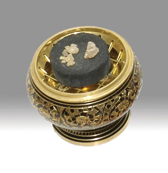 Decorative gold container with black stones on a gray background