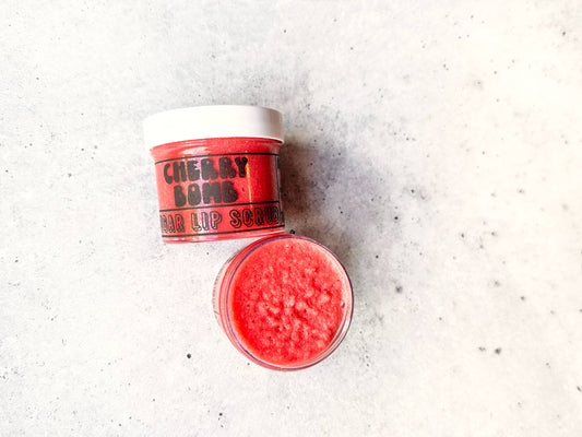 Red lip scrub with a container labeled 'Cherry Bomb' on a light gray background