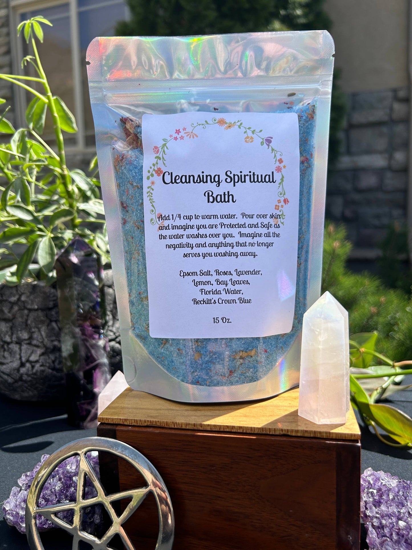 Cleansing spiritual bath product with packaging and crystal on a wooden stand outdoors.