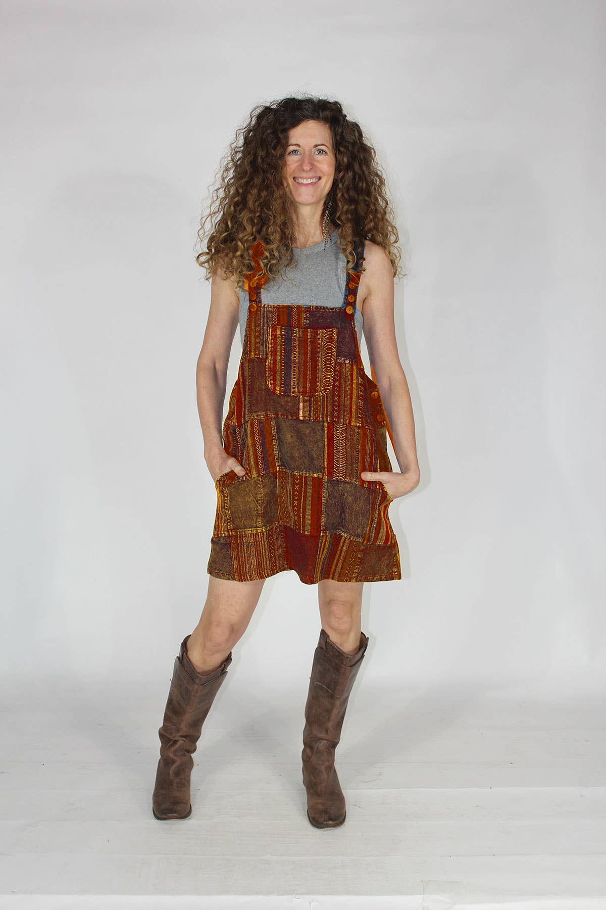 Woman wearing a patterned dress with suspenders and brown boots on a white background
