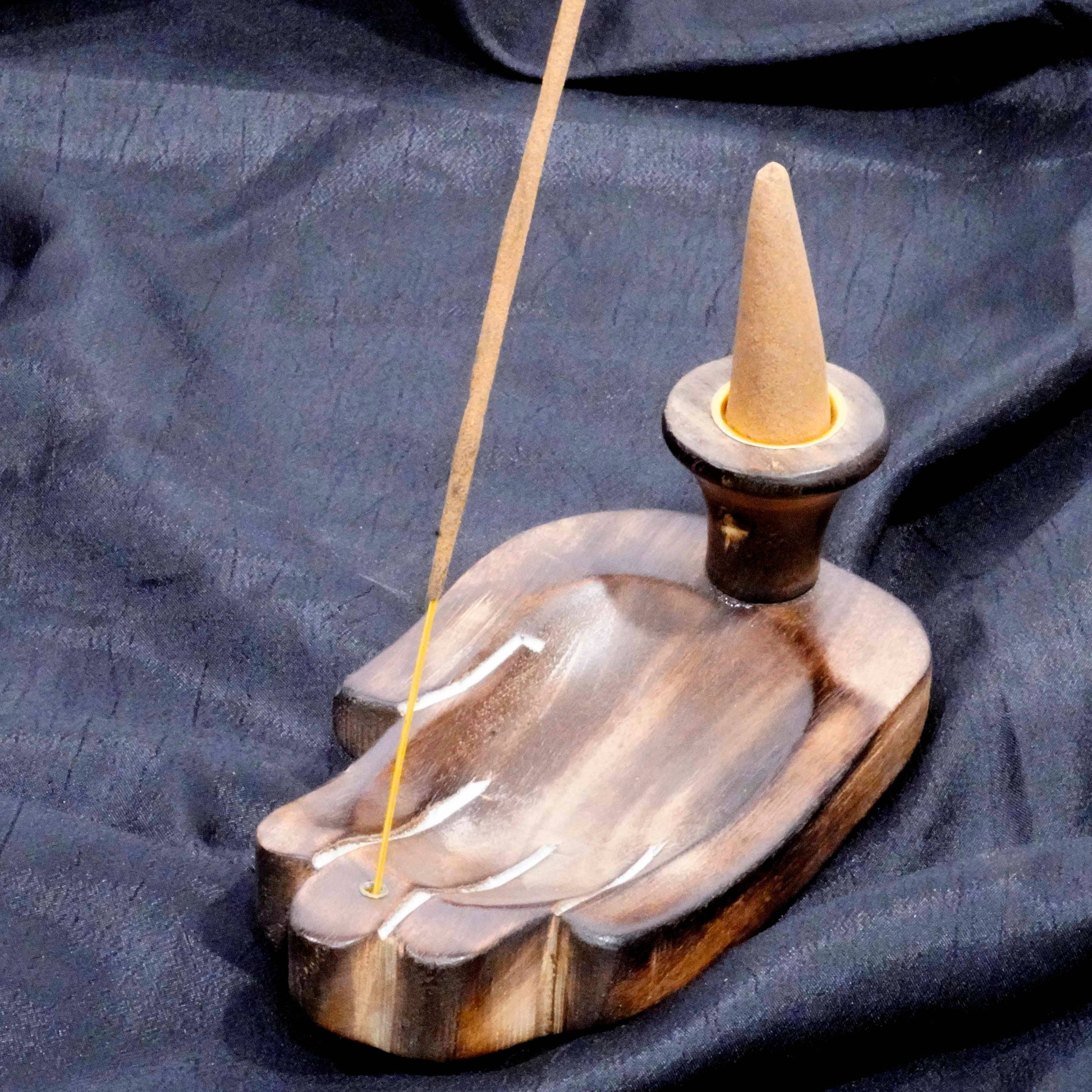 Incense burner with a cone and stick on a dark fabric background