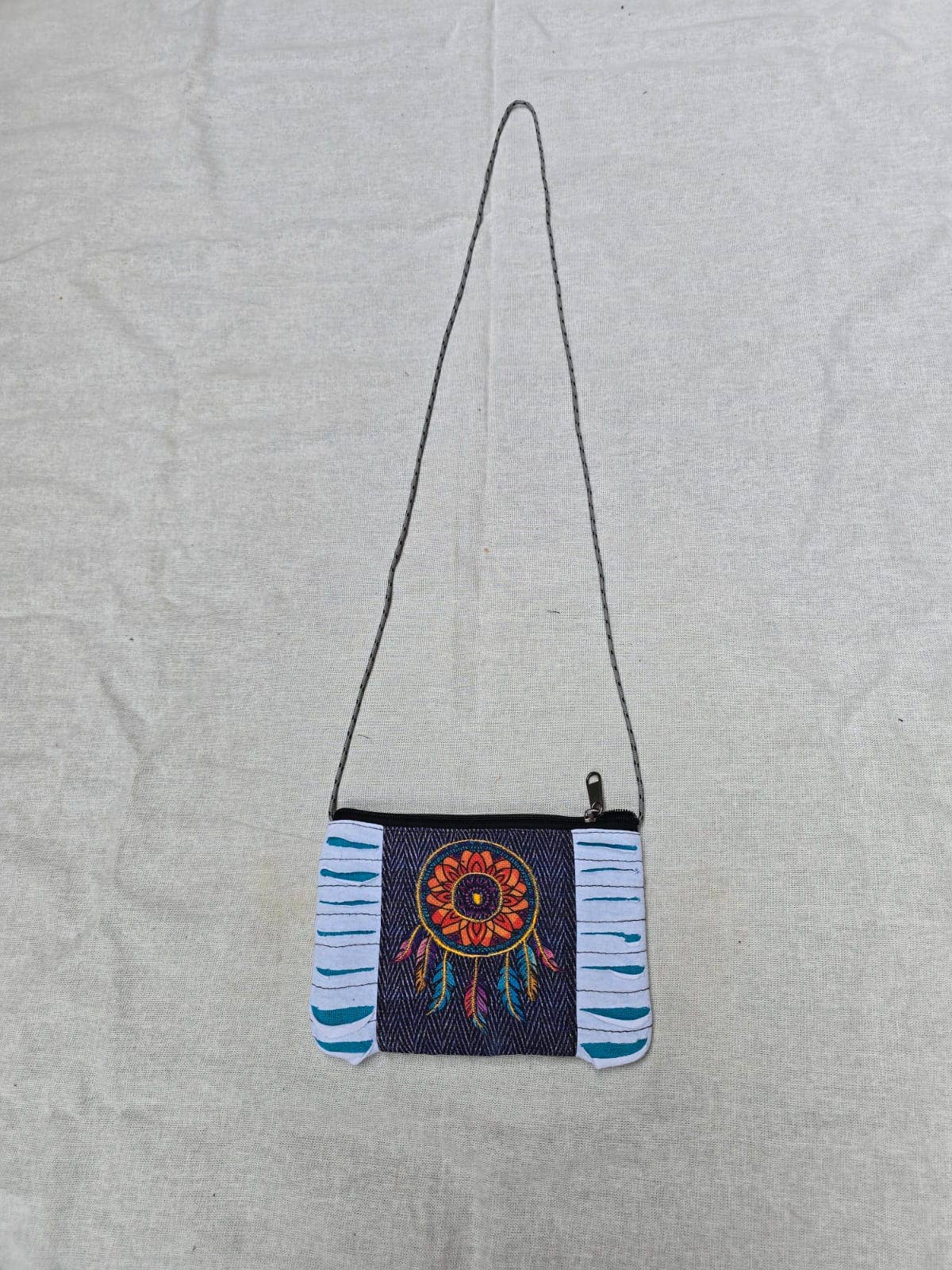 Small crossbody bag with a colorful dreamcatcher design on a light gray background