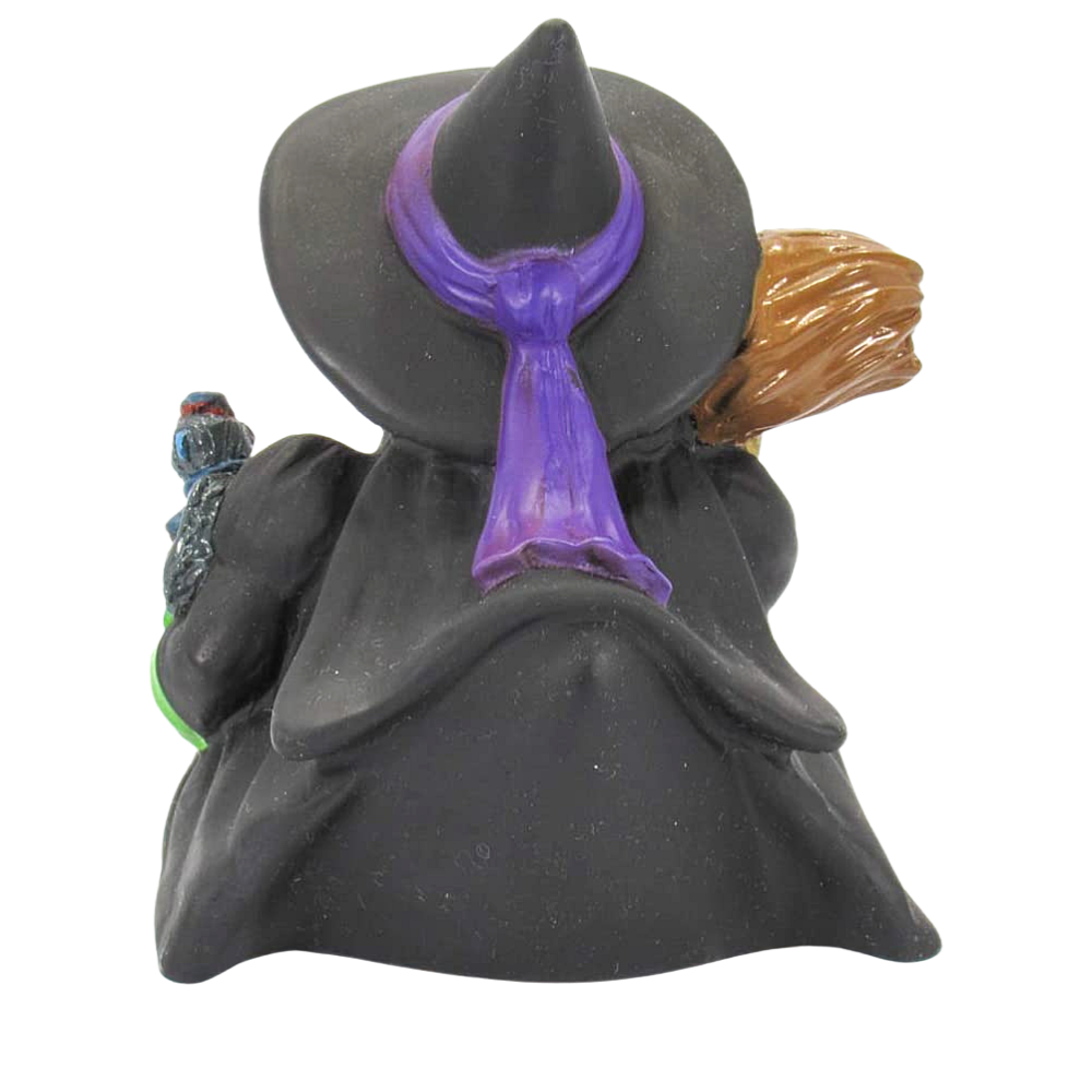 Witch figurine with black hat, purple scarf, and brown hair on a white background