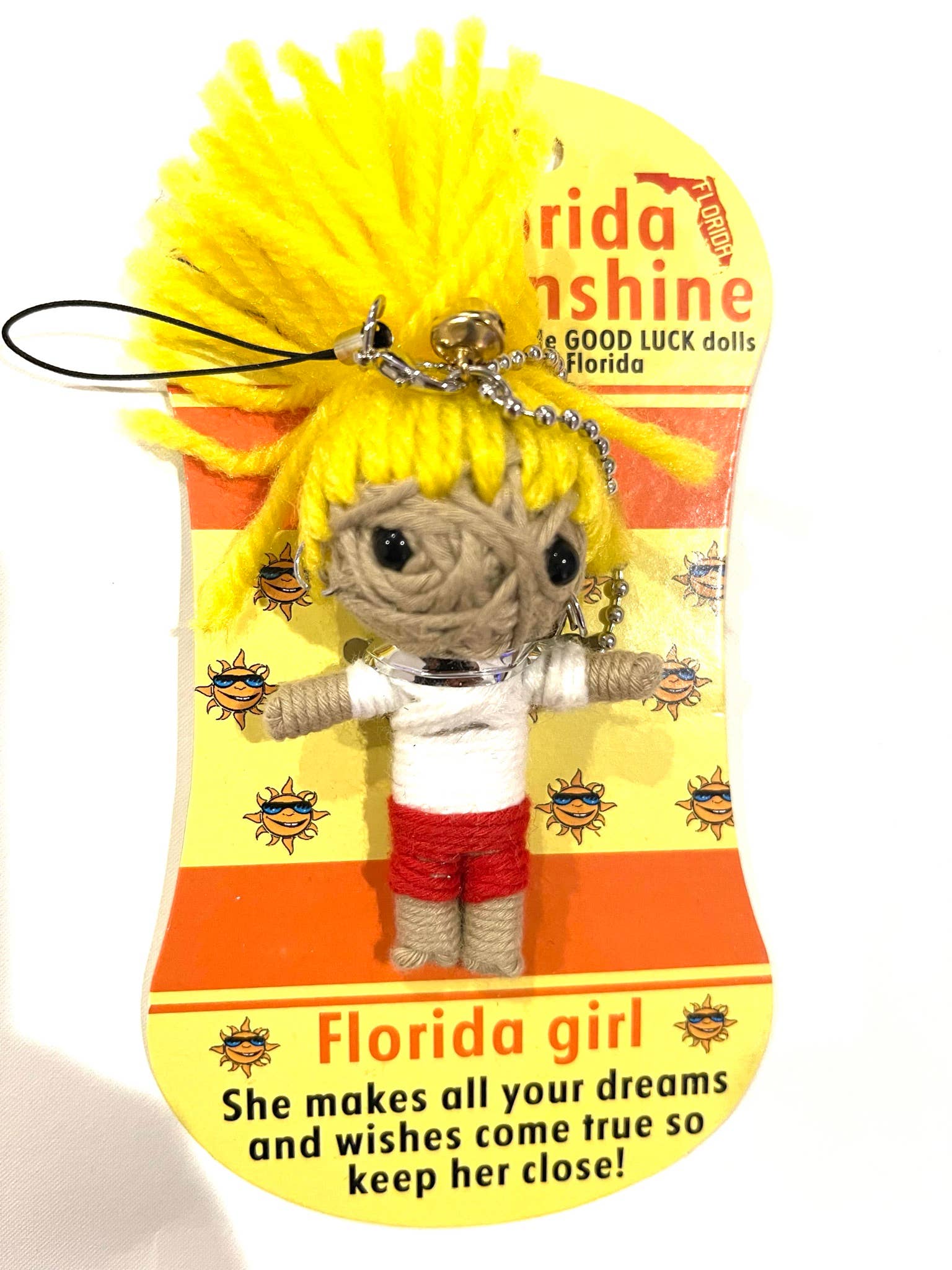 voodoo doll with Small figurine of a girl with yellow hair and red shorts on a Florida Sunshine good luck doll packaging.