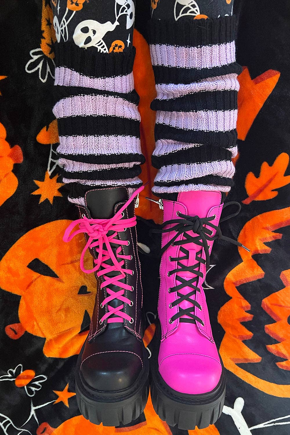 Pink and black boots with striped socks on a Halloween-themed background