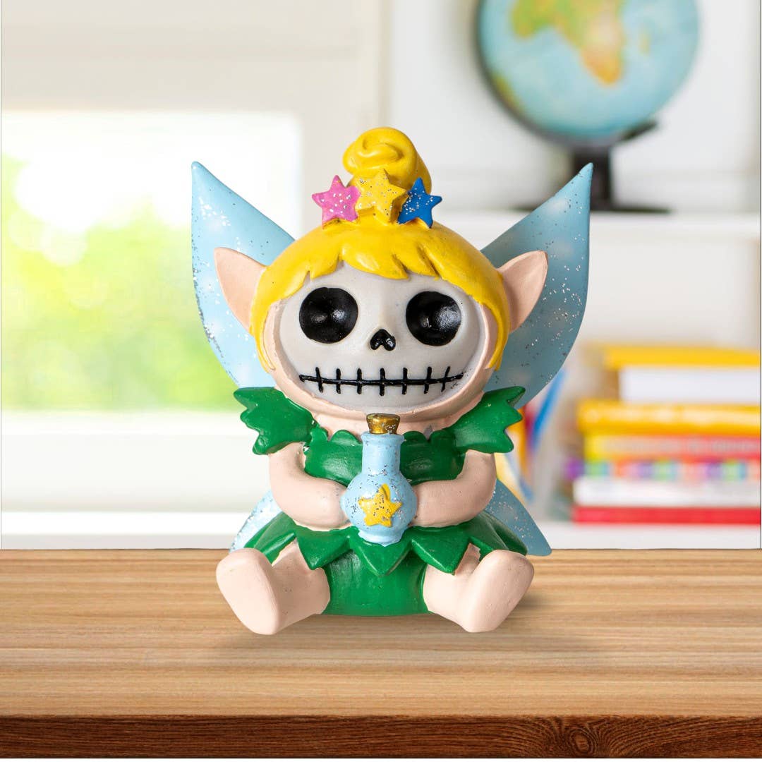 Skeleton figurine with fairy wings and green dress on a desk