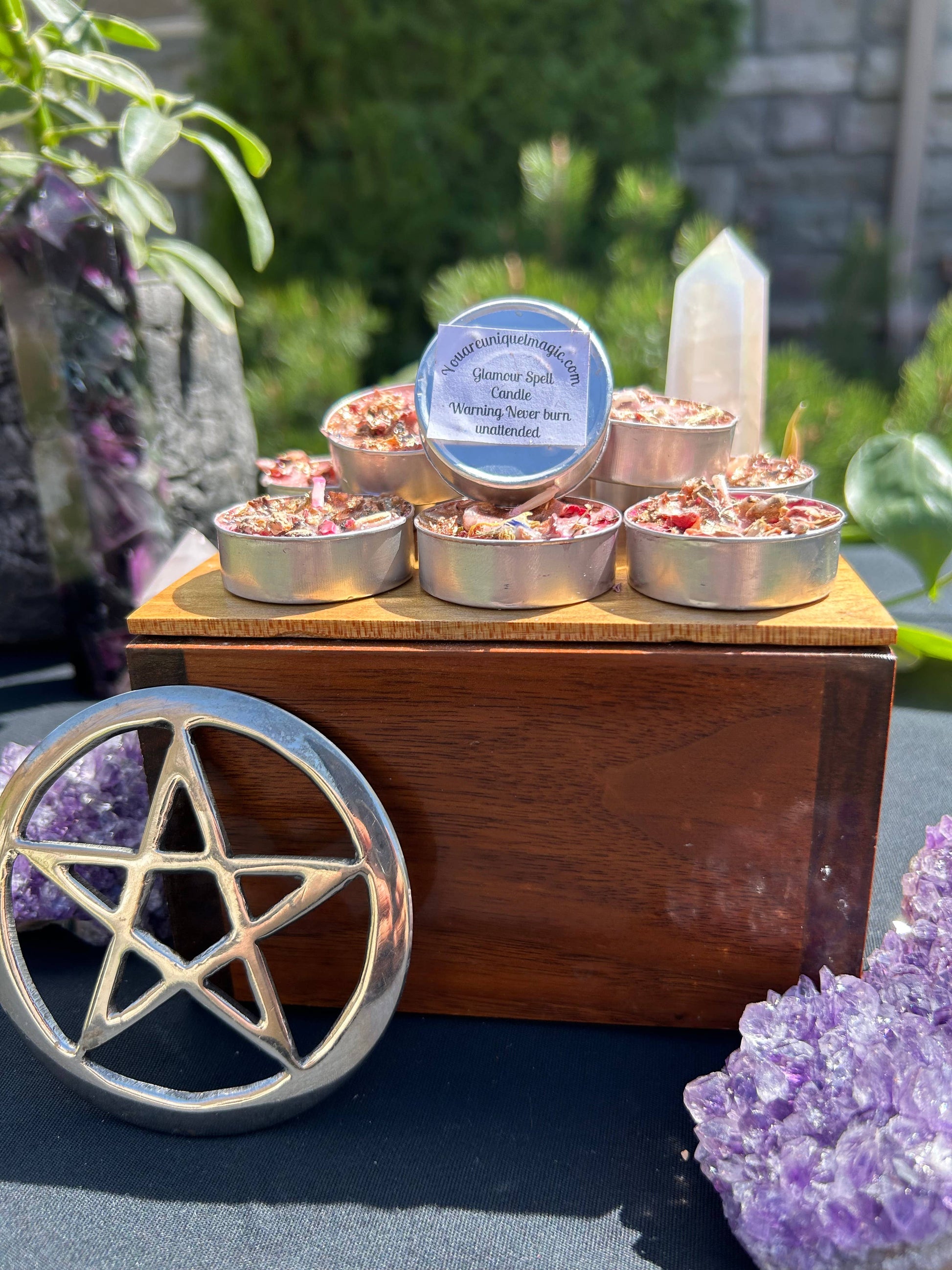 Small candles in tin containers on a wooden stand with crystals and plants in the background
