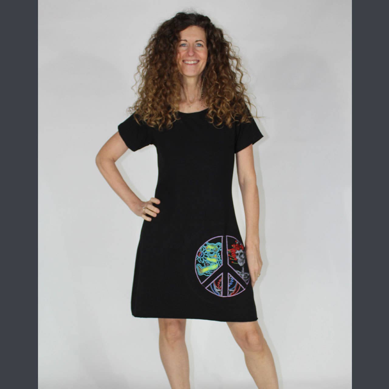 Woman wearing a black dress with a colorful peace symbol design on a plain background