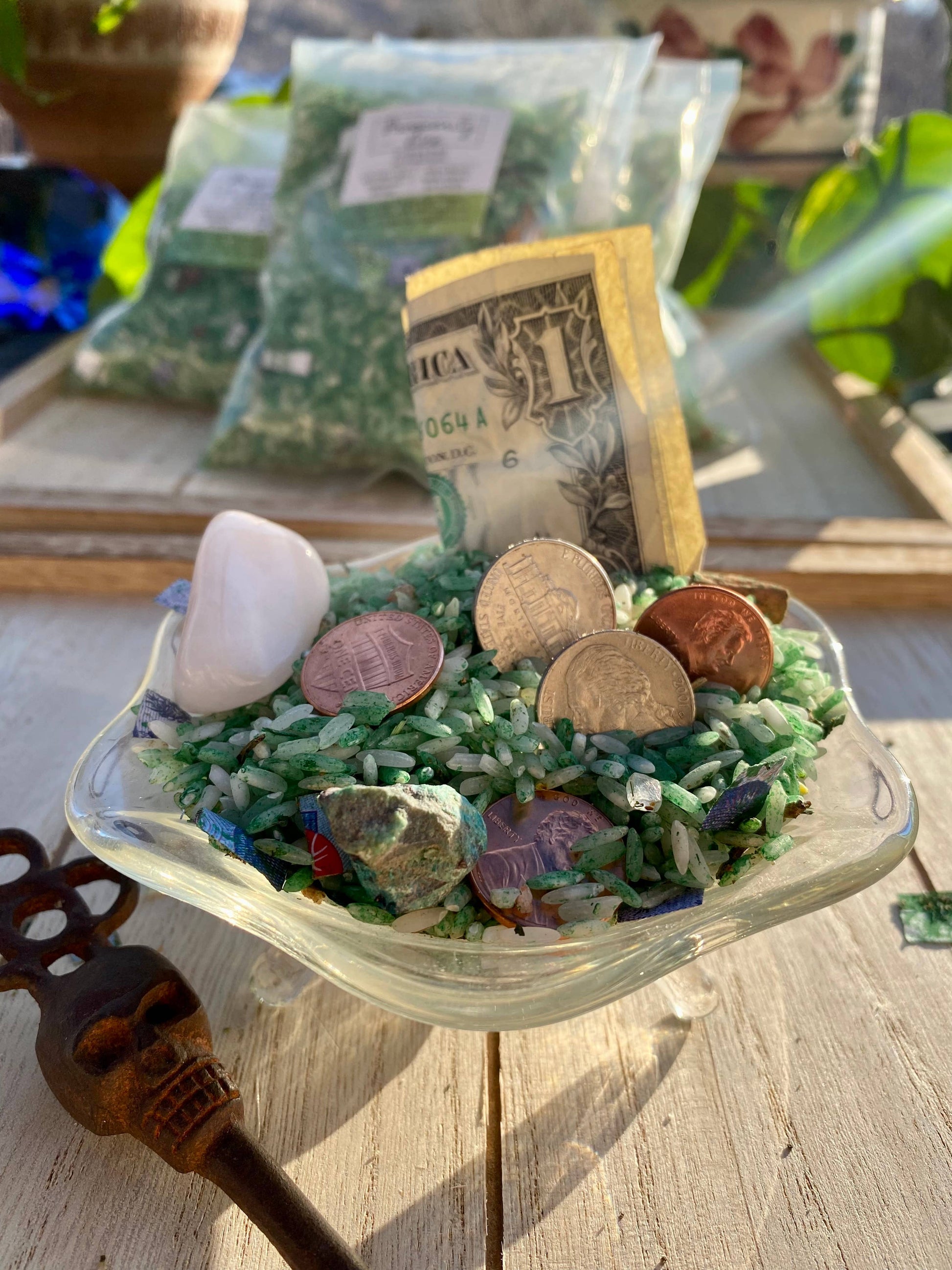 Small glass dish with decorative elements including coins, stones, and a small American flag on a wooden surface.