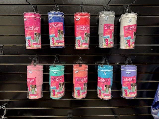 Display of colorful SIP4SIP tumblers on a black slat wall.