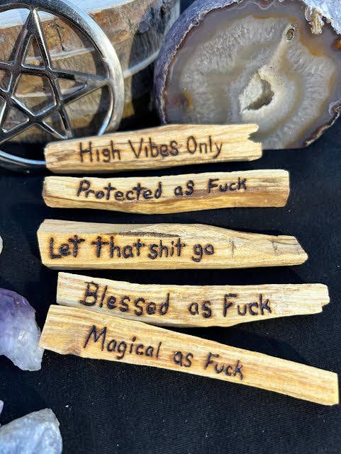 Wooden sticks with profane text on them, surrounded by crystals and a pentacle symbol.