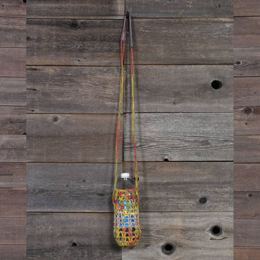 Colorful woven bag with a bottle hanging on a wooden wall