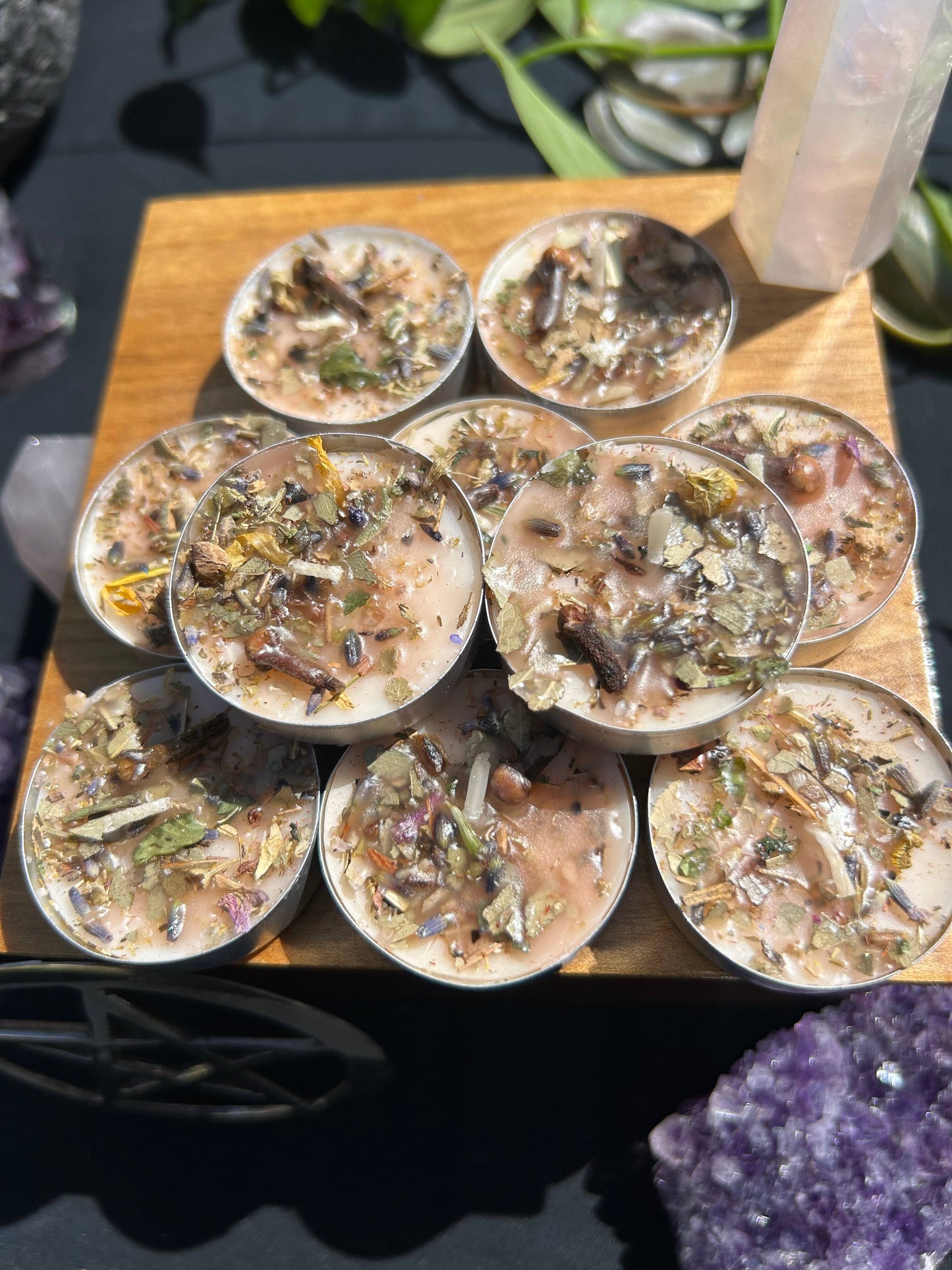 Small containers with natural ingredients on a wooden board, surrounded by crystals.