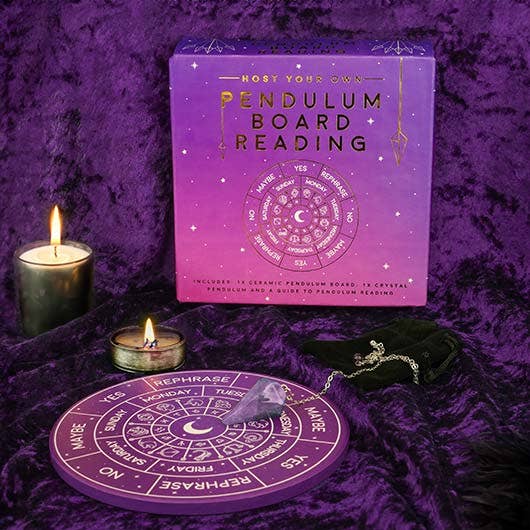 Pendulum board reading kit with purple packaging, pendulum, and candles on a purple fabric background