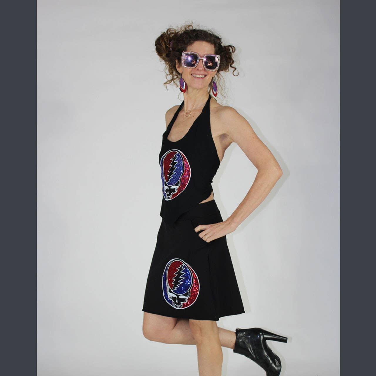 Woman wearing a black dress with colorful circular designs on a plain background