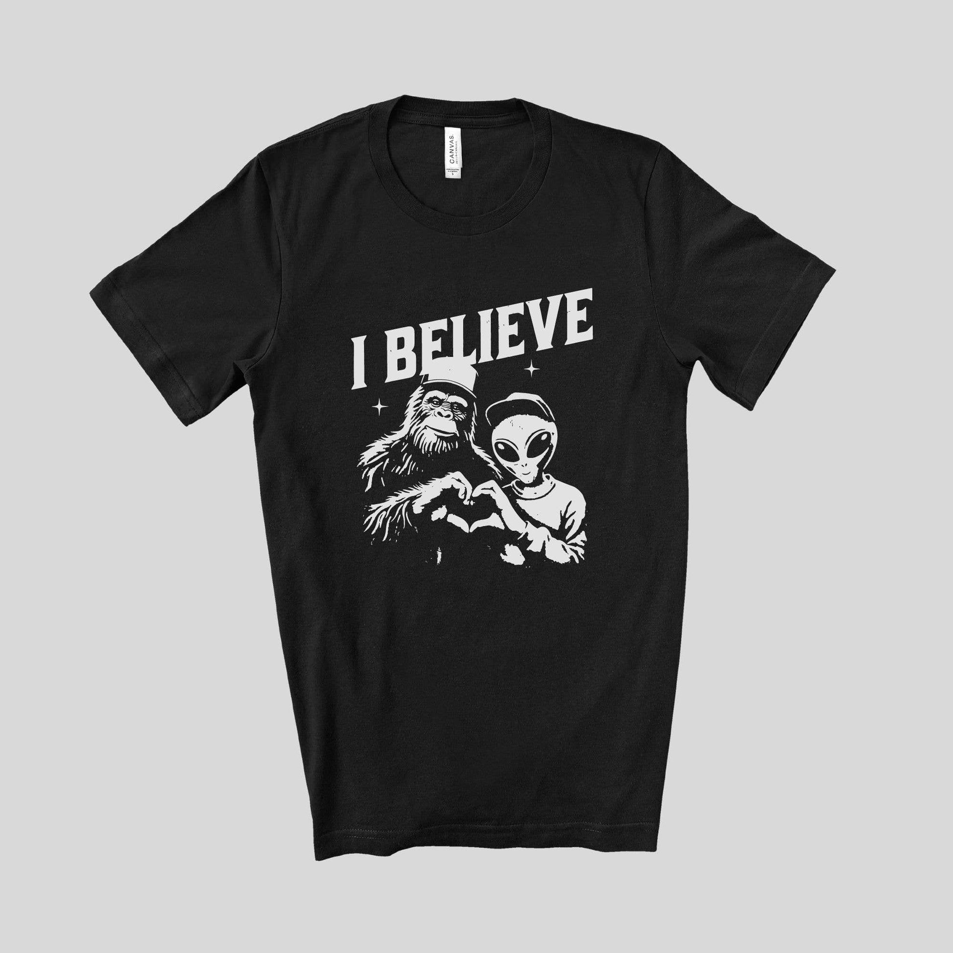 Black t-shirt with 'I Believe' graphic design featuring a monkey and alien on a gray background