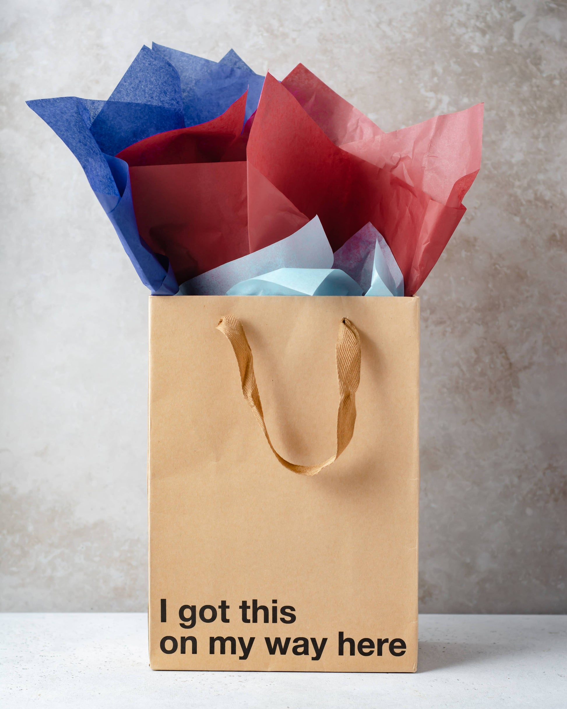Brown gift bag with colorful tissue paper and motivational text on a neutral background