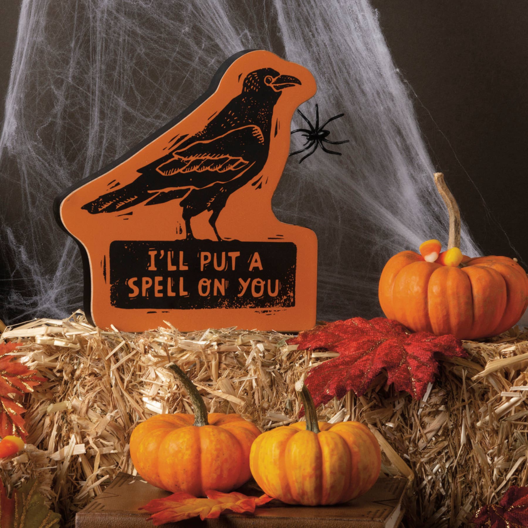 Halloween-themed decorative sign with a crow and pumpkins on hay bales.