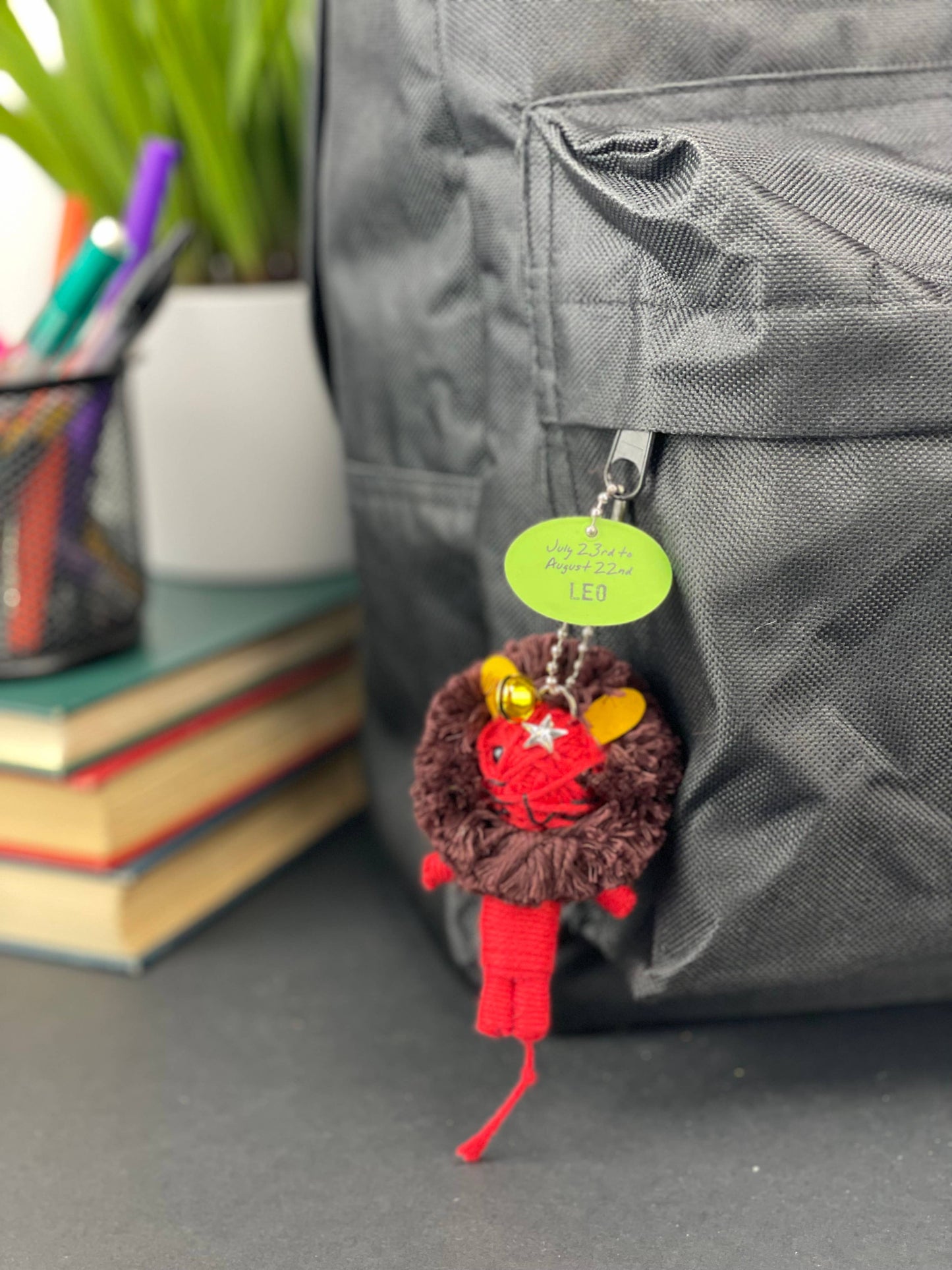 Keychain attached to a backpack with books and stationery items in the background