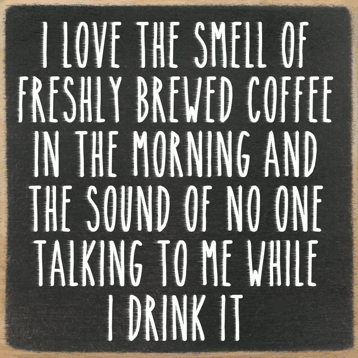 Black square sign with white text about coffee and morning solitude.