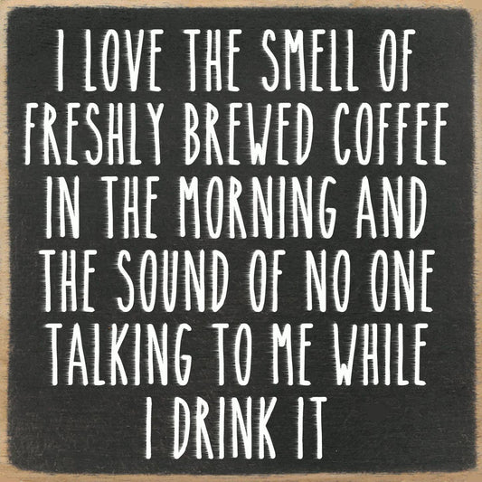 Black square sign with white text about coffee and morning solitude.