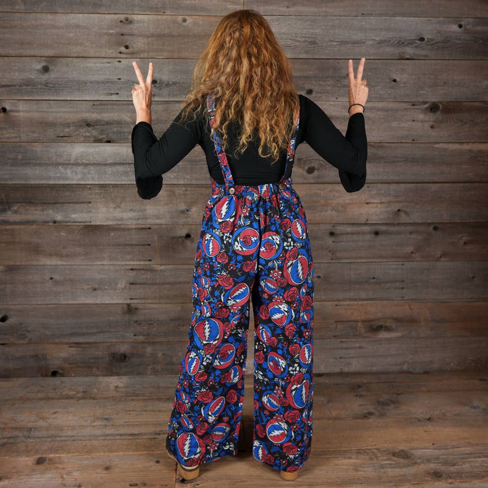 Person wearing a colorful patterned jumpsuit against a wooden wall