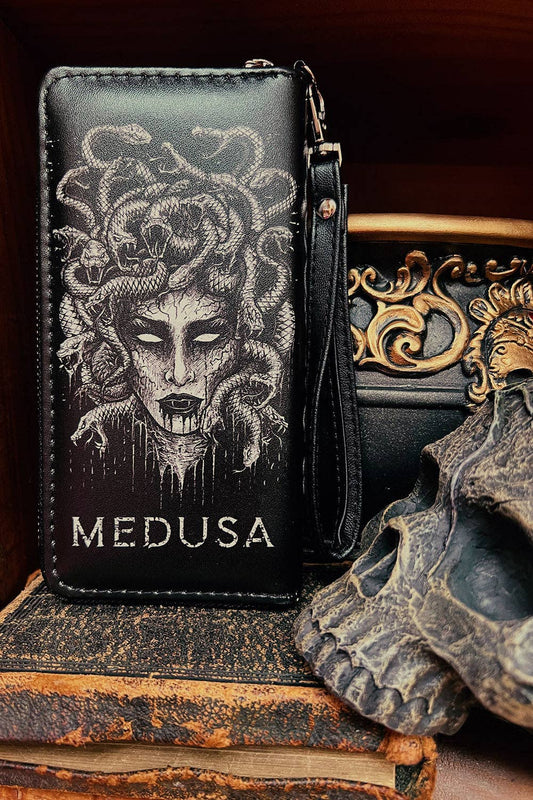 Black leather wallet featuring a detailed white illustration of Medusa and the word 'MEDUSA' printed in white, displayed on a stack of vintage books next to a skull prop.