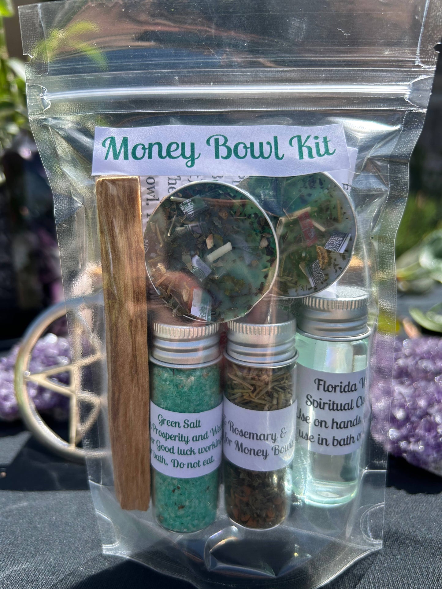 Money Bowl Kit with various items including a stick, bottles, and a label on a reflective surface.