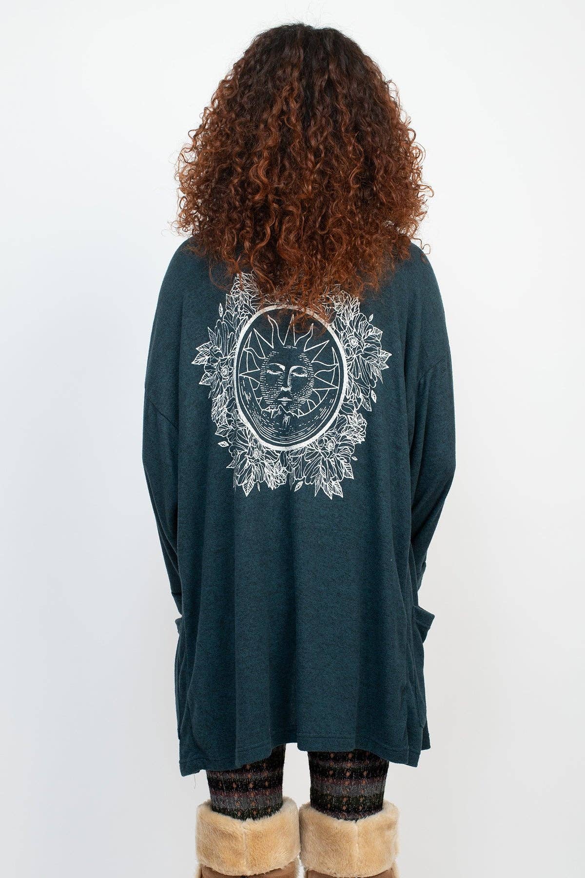 Person wearing a dark green long-sleeve top with a sun and moon design on the back, standing against a white background.