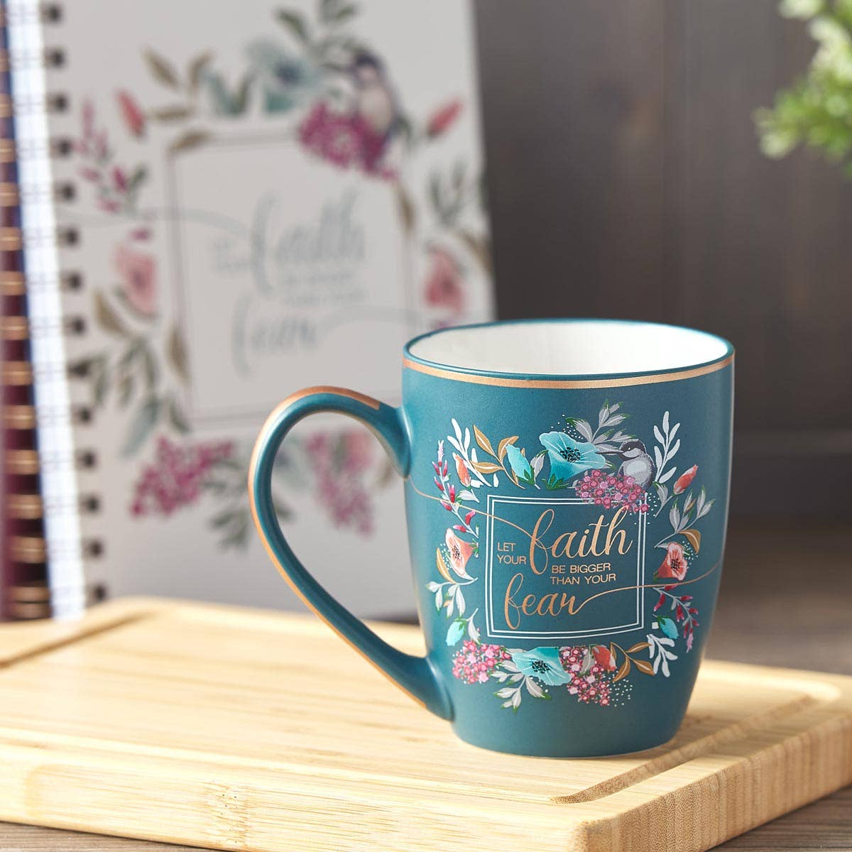 Blue mug with floral design and motivational quote on a wooden surface