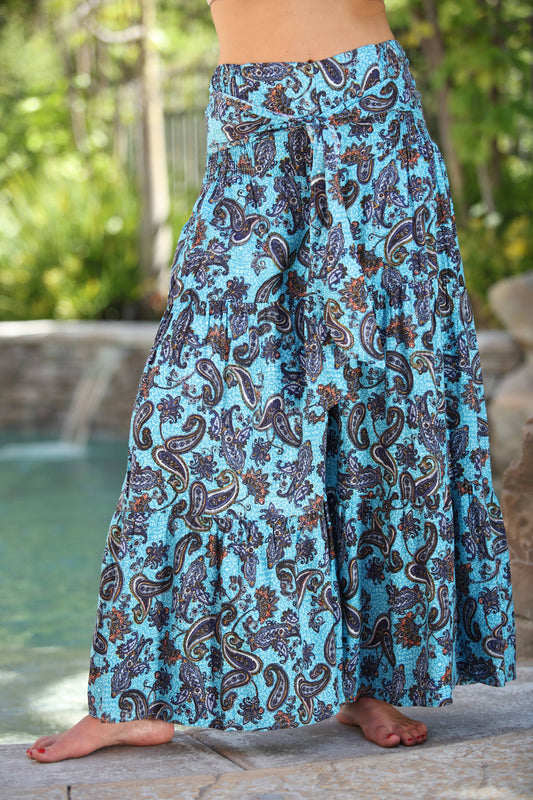 Person wearing a blue paisley patterned skirt by a poolside.